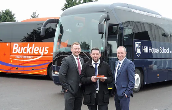three men stood in front of a buckleys private hire coach